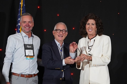 Kathy Hodgson standing with two men holding an award