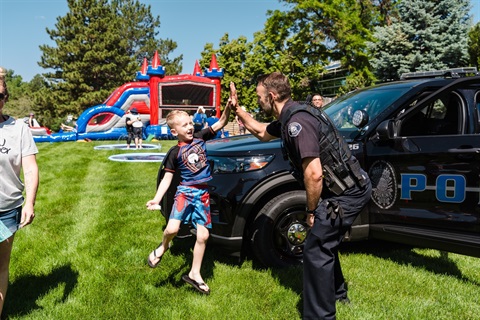 Police officer high fiving a child with a bouncy house in the background