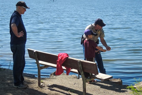 A park ranger assists a child in fishing at Bear Creek Lake Park.