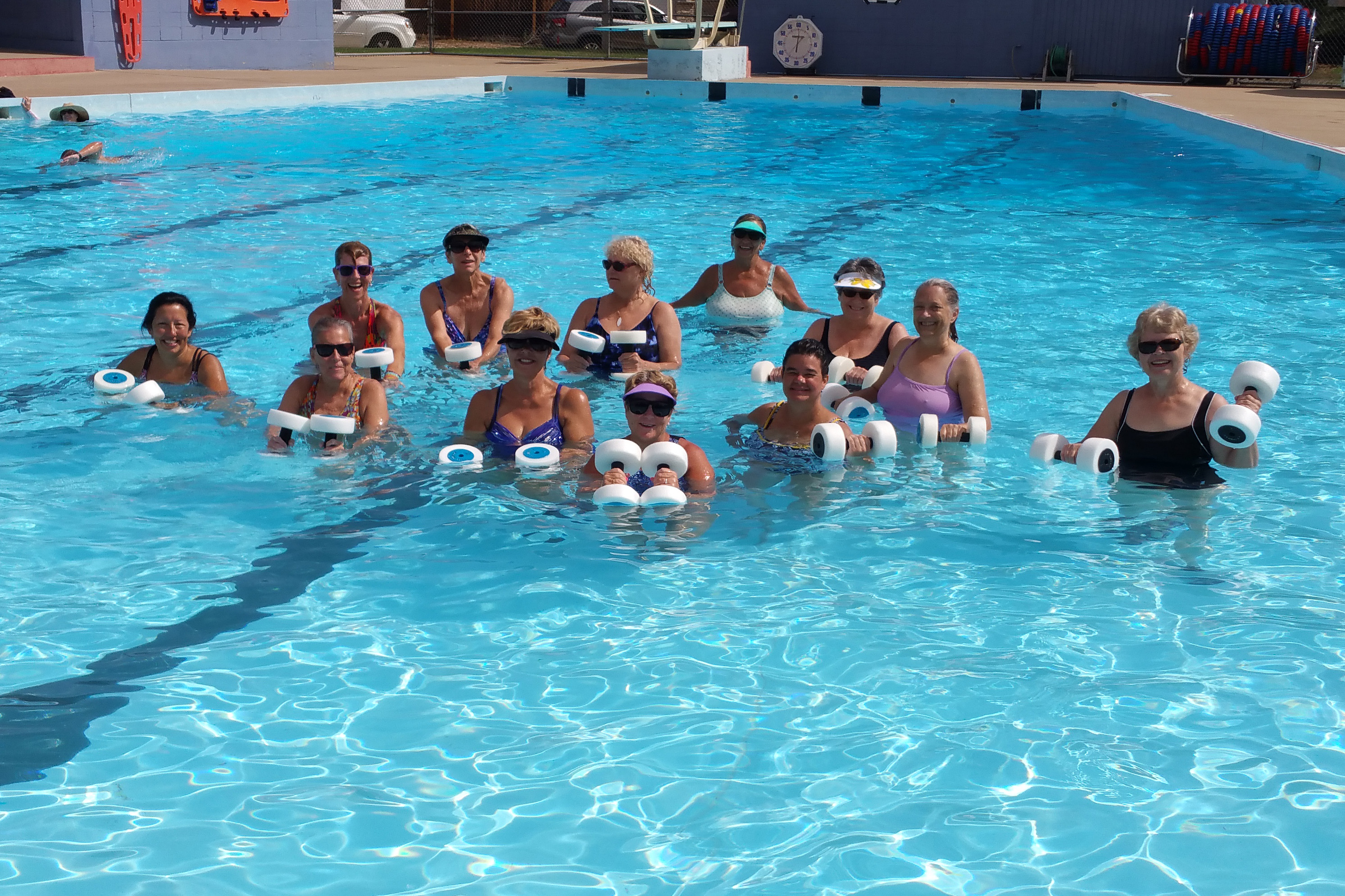 An aqua fitness class with weights takes place in a city pool.