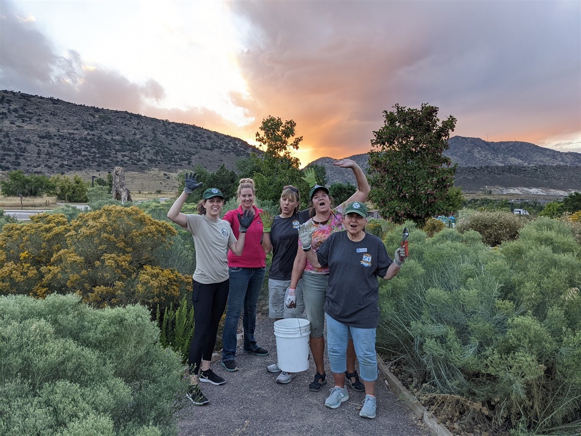Five volunteers pose in a garden.