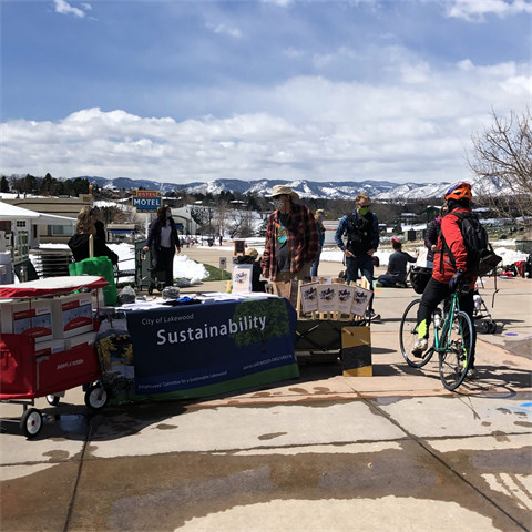 Sustainability table outside with mountains in the background. People standing around the table.