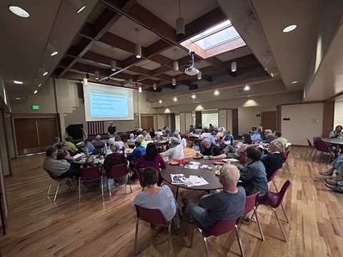 People sitting at round tables looking at a screen