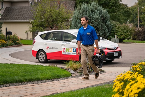 Man walking up a front path to a home with his car parked in the distance
