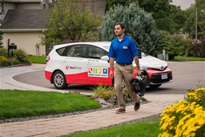 Man walking up a front path to a home with his car parked in the distance