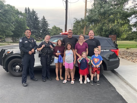 A group of people standing with Lakewood Police Agents in front of a police car