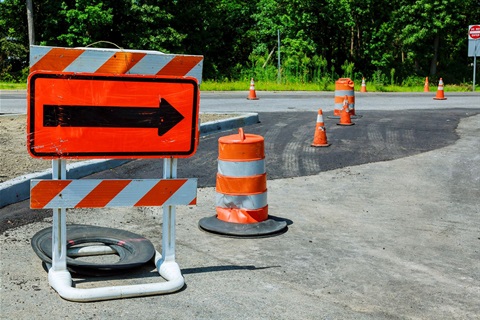 Cones along a street with an orange sign with a black arrow pointing to the right